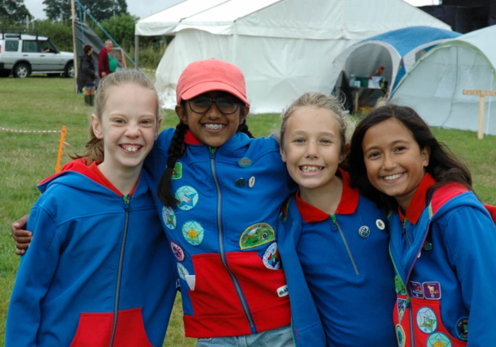 4 Guides in uniform smiling during camp